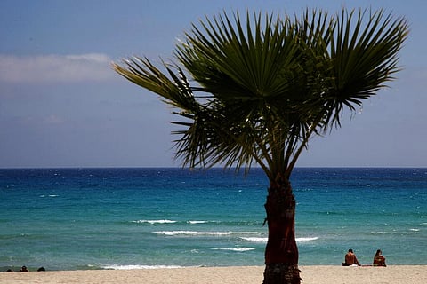 Sunbathers sit on an empty stretch of 'Landa' beach at the Cyprus seaside resort of Ayia Napa, a favorite among tourists from Europe and beyond. (Photo | AP)