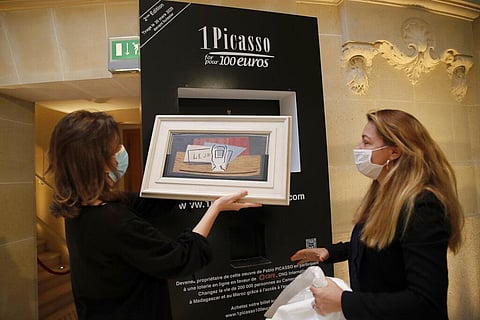 Raffle organizers Peri Cochin, left, and Arabenne Reille put the painting 'Nature morte' by Picasso in its frame at Christie's auction house, Tuesday, May 19, 2020 in Paris. (Photo | AP)