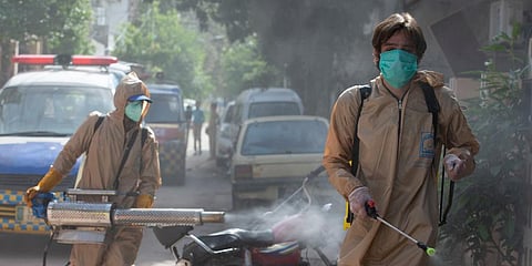 Volunteers disinfect the area which authorities sealed off after a group of people tested positive for the coronavirus, Friday, May 1, 2020. (Photo| AP)