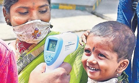 A mother and child get their temperatures checked before boarding a bus in Bengaluru on Tuesday | SHRIRAM BN