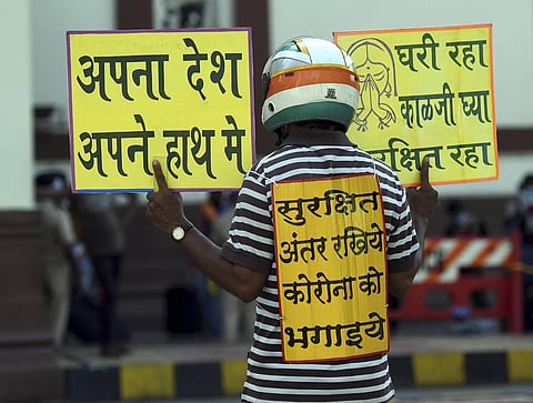 A social worker displays placards to create awareness about social distancing amid ongoing COVID-19 lockdown in Mumbai Tuesday May 12 2020. (Photo | PTI)