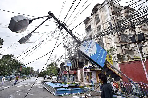 Passersby look at an uprooted lamp post following super cyclone 'Amphan' in Kolkata Thursday. (Photo | PTI)