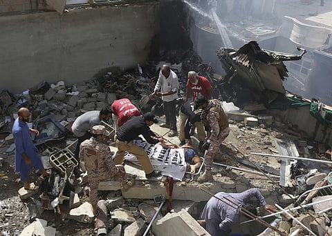 Volunteers cover the dead body of a plane crash victim at the site of the crash. (Photo | AP)