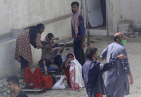 Residents of an area hit by a plane crash wait for medical help in Karachi, Pakistan. (Photo | AP)