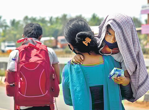A woman walking along the NH-16 roadway en route to Vijayawada under the scorching sun carrying her baby | shiba prasad sahu