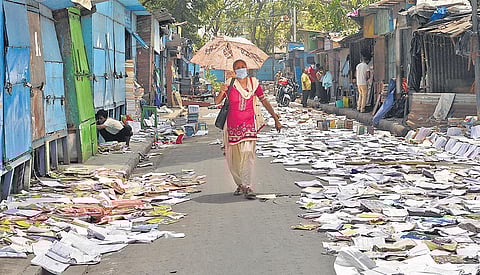 A woman walks past books kept on a road to dry after Cyclone Amphan, in Kolkata on Saturday | PTI