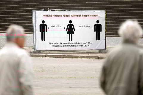 People walk in front of a poster wall displaying the distance rules at the cathedral place in Erfurt, central Germany, Monday, May 25, 2020. (Photo | AP)