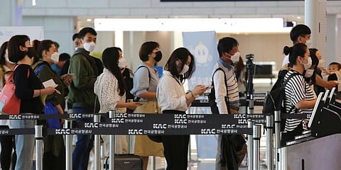 Passengers wearing face masks line up to board their planes at the domestic flight terminal of Gimpo airport in Seoul, South Korea. (Photo | AP)