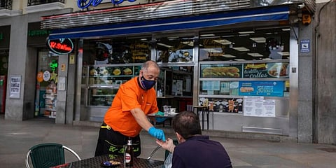 A waiter attends a customer at a bar terrace in Madrid, Spain. (Photo | AP)
