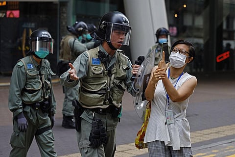 Riot policeman pushes a woman as she is taking a photograph of the detained protesters at the area in Mongkok, Hong Kong, Wednesday, May 27, 2020. (Photo | AP)
