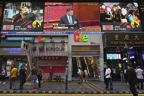 Pedestrians walk under a giant screen showing live telecast of Chinese President Xi Jinping, top center, at the closing session of the National People's Congress, in Hong Kong, Thursday, May 28, 2020. China’s ceremonial legislature on Thursday endorsed a 