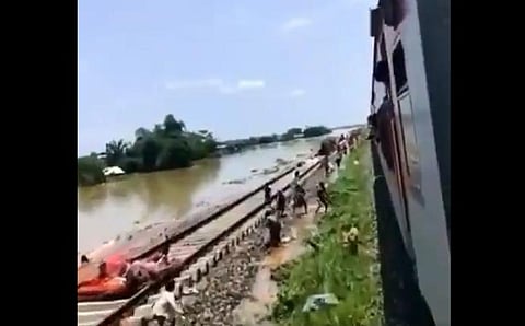 A screengrab of the video shows people collecting edibles thrown by the passengers from the running train (Twitter | @ZoramthangaCM)