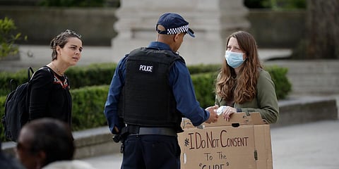 A police officer speaks to a coronavirus anti-lockdown protester holding a placard in Parliament Square, London. (Photo| AP)