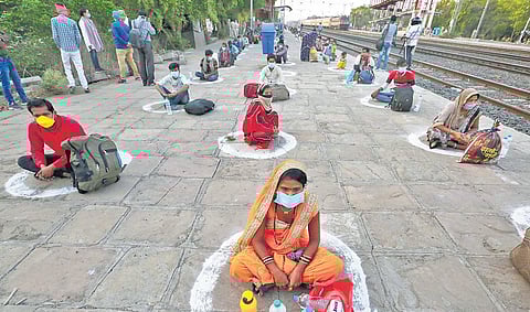 Migrant labourers sit in circles marked for them for social distancing at a railway platform in Bhopal. (Photo | PTI)