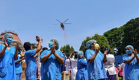 An Indian Air Force (IAF) helicopter showers flower petals on medics to applaud them for their services, during the nationwide lockdown in the wake of coronavirus pandemic, in Bengaluru, Sunday, May 03, 2020. (Photo | PTI)