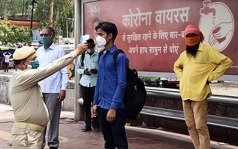 Delhi Home Guard personnel thermal screening people before they are allowed to board buses at Anand Vihar bus stop on May 29 2020 in New Delhi. (Photo | Parveen Negi/EPS)