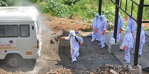 Municipal workers wearing protective suits sanitize an ambulance after transporting the body of a COVID-19 patient for cremation in Uttar Pradesh. (Photo | PTI)