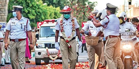 A traffic police constable, who was discharged after being treated for COVID-19, is welcomed by his colleagues outside Victoria Hospital, in Bengaluru. (Photo| Shriram BN, EPS)