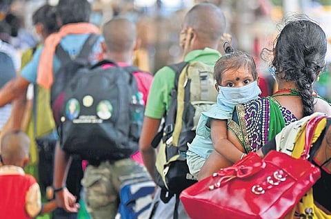Waiting in line along with her mother to go home, a baby wears a mask, at Chennai Central Railway Station.(Photo| Martin Louis, EPS)