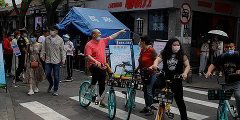 A group of bicyclists wearing protective face masks to help curb the spread of the new coronavirus prepare to leave after they were prevented to enter the capital's popular tourist spot of Nanluonguxiang. (Photo| AP)