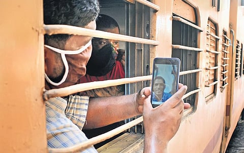 A migrant labourer video calling his brother, who is also in Kozhikode and was not able to board the train, after he got a seat in the train from Kozhikode railway station which will take him to Bihar. (Photo | EPS/Manu R Mavelil)