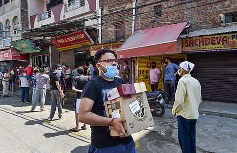 A customer carries alcohol after purchasing from a wine shop during the ongoing COVID-19 nationwide lockdown at Chander Nagar in East Delhi. (Photo | PTI)