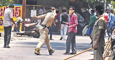 A cop lathicharge a man near a closed liquor store in Vijayawada. (photo | EPS/P Ravindra Babu)