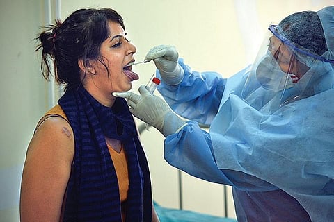 A health worker collects throat swabs at a government hospital. (Photo | EPS/NAGARAJA GADEKAL)