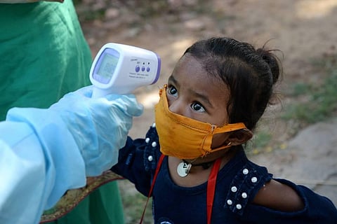 A medic screens a child of a migrant worker as they wait to board a train to Jharkhand during the ongoing COVID-19 nationwide lockdown in Jalandhar. (Photo | PTI)