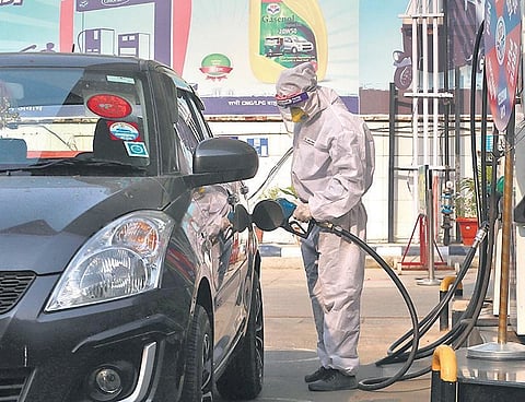 A petrol pump employee, wearing protective gear, re-fuels a car. (Photo | Shekhar Yadav, EPS)