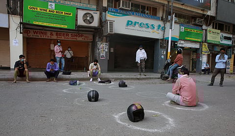 People have kept their belongings like helmets bottles sacks to mark their positions in queues outside liquor shops in Vasant Vihar in New Delhi on Friday. (Photo | Shekhar Yadav/EPS)