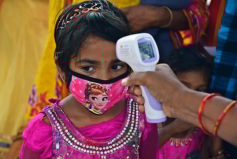 Pink power Health worker checking temperature of a young migrant girl form UP who was seen wearing matching fancy mask at palace grounds on Wednesday in Bengaluru. (Photo | Shriram BN/EPS)