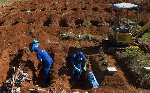 A cemetery worker exhumes the body of a person buried three years ago at the Vila Formosa cemetery, which does not charge families for the gravesites, in Sao Paulo, Brazil, Friday, June 12, 2020. Three years after burials, remains are routinely exhumated 