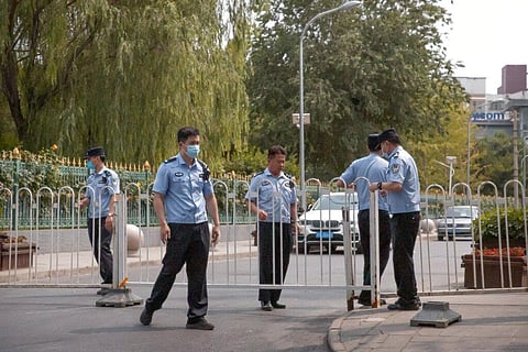 Police officers pull a barricade across a road leading to the a residential neighborhood near the Xinfadi wholesale food market district in Beijing, Saturday, June 13, 2020. (Photo | AP)