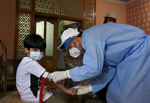 A health worker takes blood sample of a boy during door-to-door testing and screening facility for the coronavirus in Pakistan. (Photo| AP)