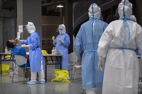 A worker in a protective suit swabs the throat of a man at a COVID-19 testing site for those who were potentially exposed to the coronavirus outbreak at a wholesale food market in Beijing. (Photo | AP)