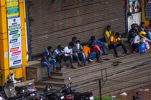 Violating social distancing norms people busy watching their mobile phones near a closed shopping mall at Unit-2 market in Bhubaneswar on Monday. (Photo | Biswanath Swain/EPS)