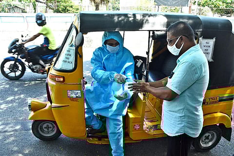 Wearing a PPE kit, an auto driver in Chennai gives hand sanitiser to a commuter in the city. (Photo | Ashwin Prasath, EPS)