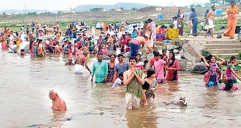 People take bath in Godavari after solar eclipse ends at Dharmapuri, on Sunday