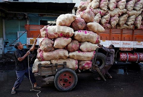 Labourers load sacks filled with coconuts on a hand cart at a wholesale market in Ahmedabad. (Photo | Reuters)
