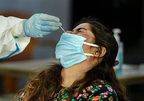 A medic takes swab samples for COVID-19 infection from a woman at a testing centre inside a government school in New Delhi. (Photo | PTI)