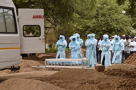 Relatives along with health workers and volunteers wearing personal protective equipment offer prayers before carrying the body of a COVID-19 victim for burial. (Photo| PTI)