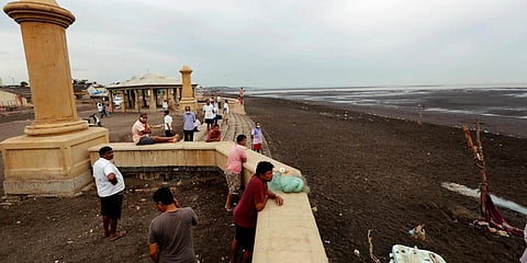 People look on at the sea as they spend their time at a beach off the Arabian Sea before Cyclone Nisarga makes landfall in Daman. (Photo| PTI)