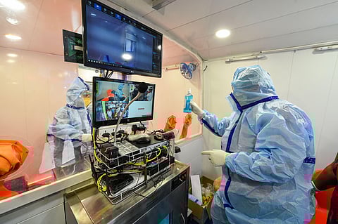 Medics wearing protective kits work inside a mobile coronavirus testing facility bus in New Delhi. (Photo | PTI)
