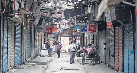People walk past closed shops at Lajpat Rai Market in Delhi on Thursday as the market association has decided to keep the establishments closed to curb the spread of coronavirus in New Delhi on Thursday| ANIL SHAKYA