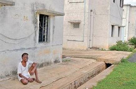 A watchman sits outside a vacant flat at Doddamannina Gudde in Ramanagara district on Friday | Meghana Sastry