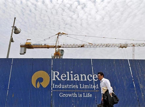 A man walks past an advertisement of Reliance Industries Limited at a construction site in Mumbai. (File photo| Reuters)