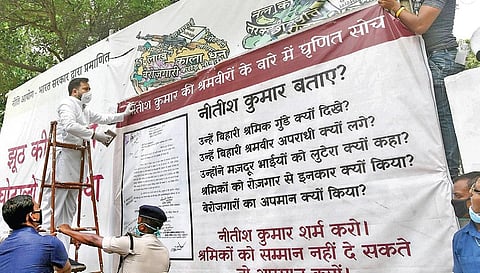 RJD leader Tejashwi Yadav puts up a poster against the state government (Photo | PTI)