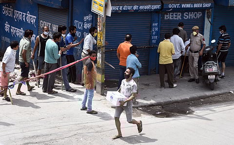 A customer carries alcohol after purchasing from a wine shop during the ongoing COVID-19 nationwide lockdown at Vishwas Nagar in East Delhi. (File photo| Parveen Negi/EPS)