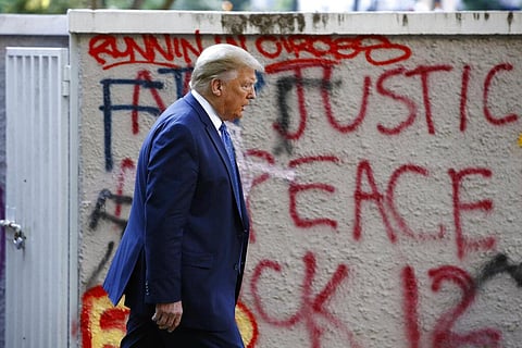 President Donald Trump walks from the White House past graffiti in Lafayette Park to visit St. John's Church in Washington on Monday, June 1, 2020. (Photo | AP)